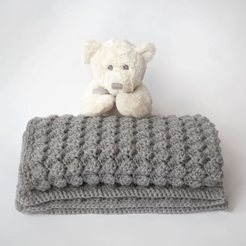 Plush gray velvet shell stitch crochet baby blanket folded with visible fan shells
